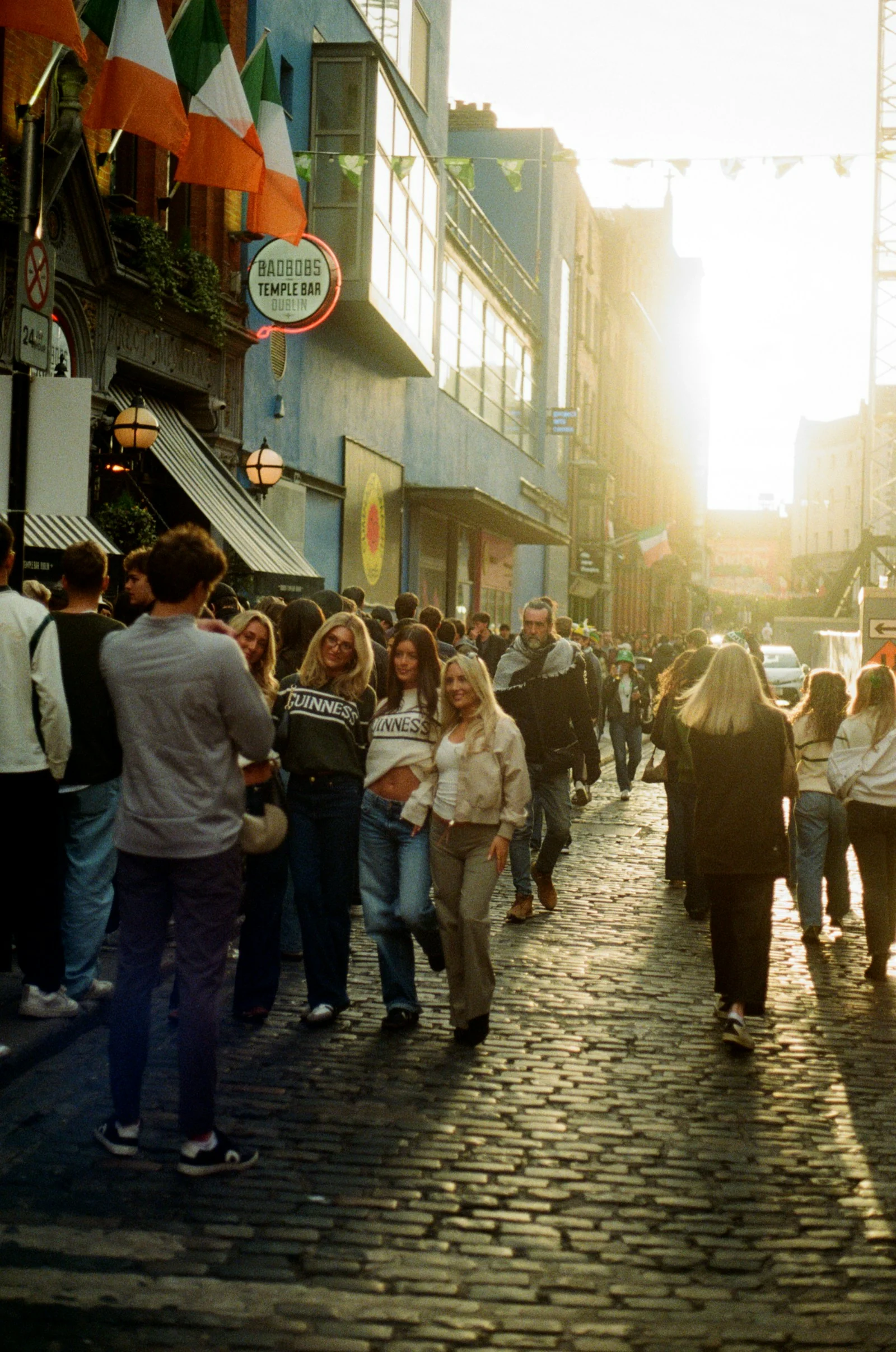 A group of friends smiling for a photograph on a sunlit cobbled street in Temple Bar, Dublin